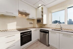 Een moderne keuken met witte kastjes, een magnetron, een oven en een vaatwasser.