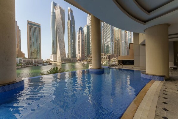 A rooftop pool with a view of high-rise buildings and a body of water in the background.