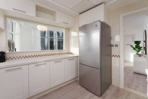 A modern kitchen with white cabinets, a stainless steel refrigerator, a window with blinds, and a checkered tile backsplash. - Exquisite 2-Bedroom with Panoramic Marina view (Dubai)