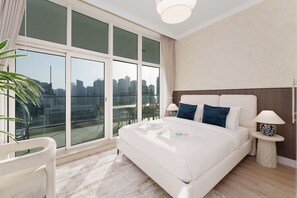 Een moderne hotelkamer met een groot bed, twee nachtkastjes, uitzicht over de stad en een balkon.