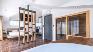 Una habitación de hotel moderna con una cama grande, una separación de madera, una puerta corredera y una bañera de hidromasaje.