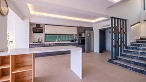Una cocina moderna con una isla central, electrodomésticos integrados y una escalera de diseño único.