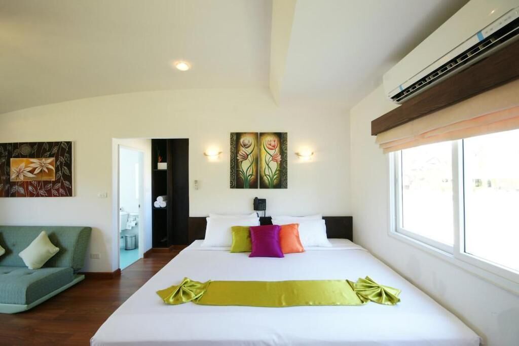 Una habitación de hotel con una cama grande, un sofá verde y obras de arte en las paredes.