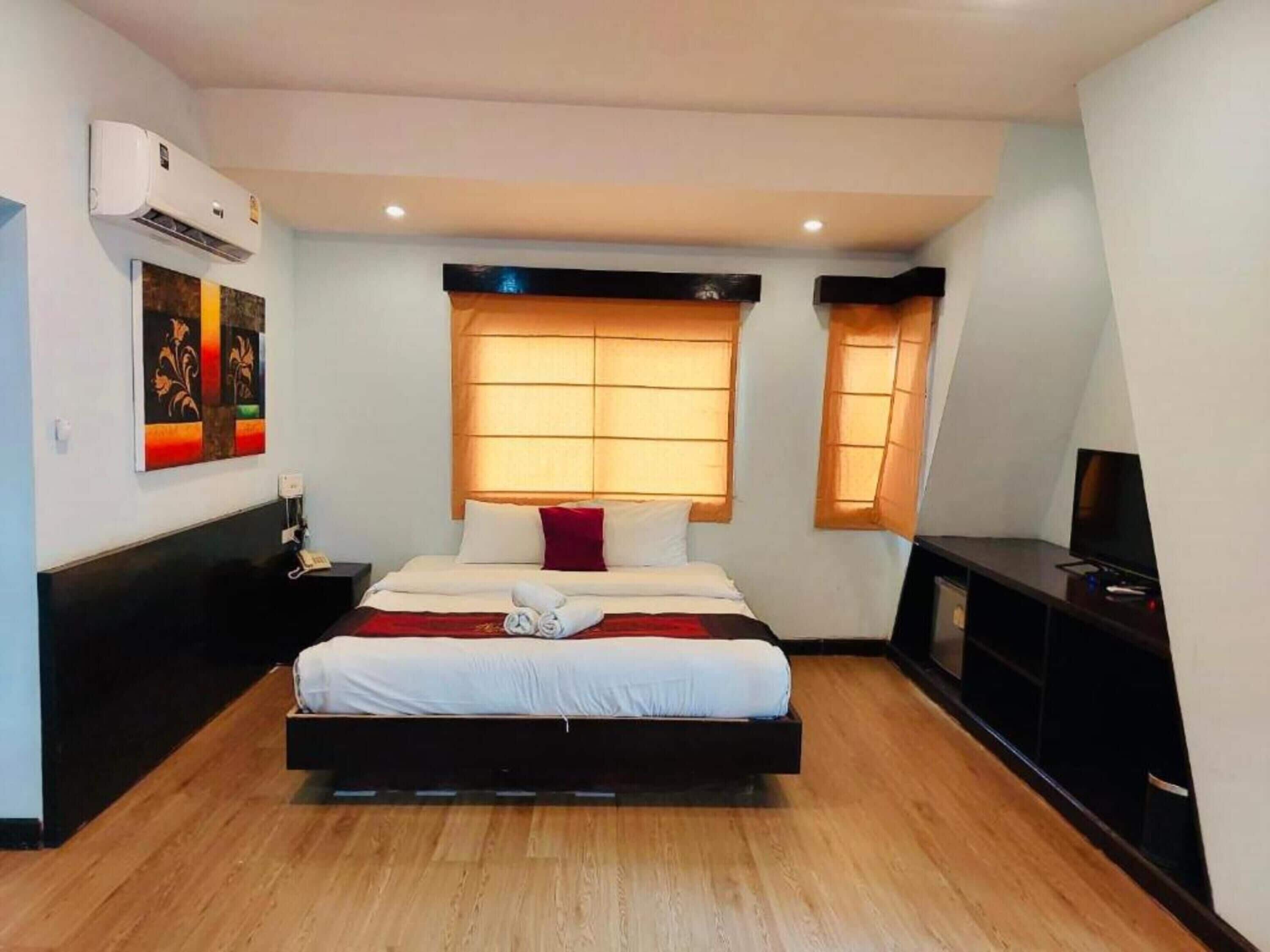 A modern hotel room with a large bed, a flat-screen TV, and a wall-mounted air conditioner.