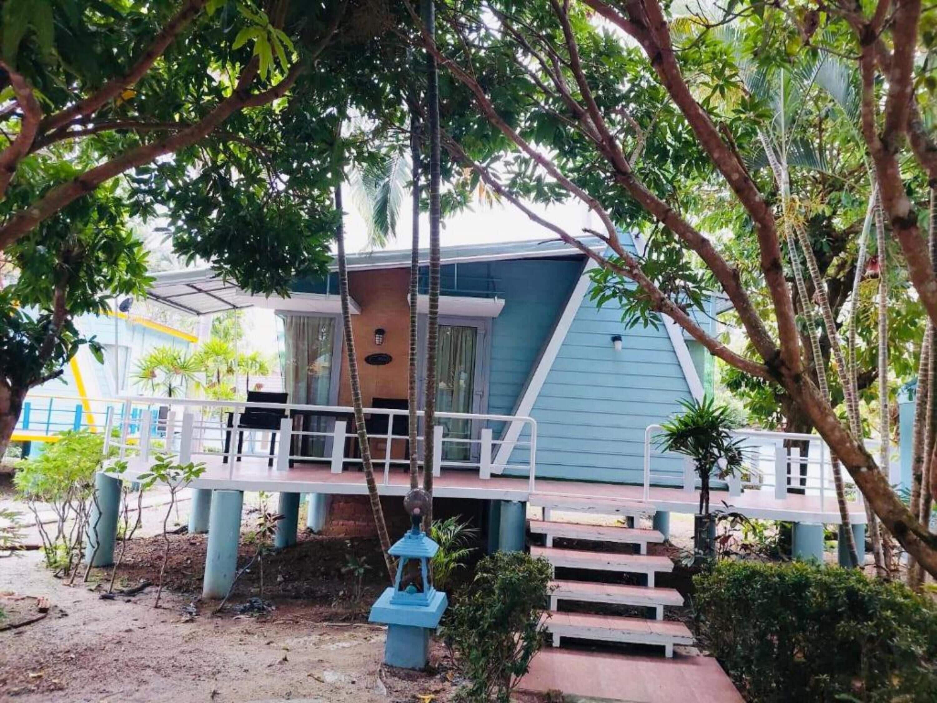 Un edificio de dos pisos con fachada azul, un porche cubierto y una escalera que conduce a la entrada.