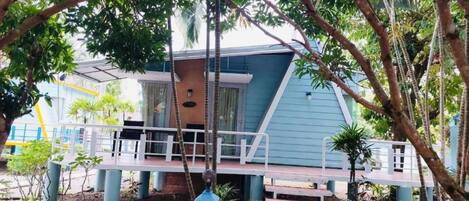 Un edificio de dos pisos con fachada azul, un porche cubierto y una escalera que conduce a la entrada.