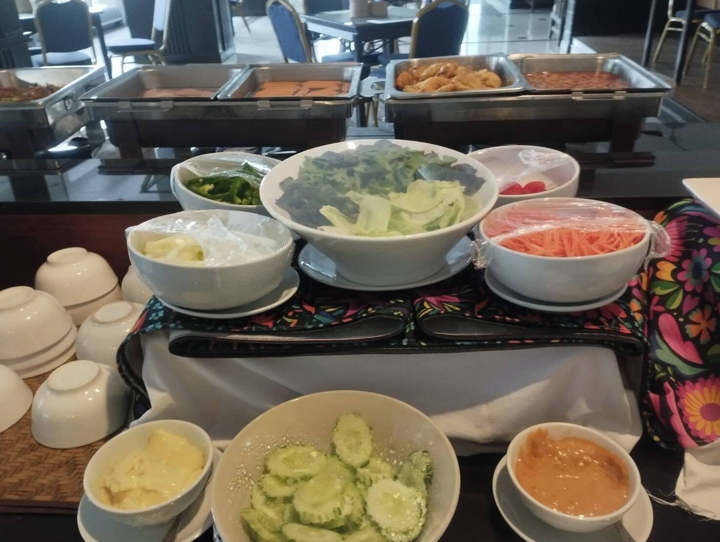Una mesa de buffet con diversos alimentos, como ensaladas, verduras y salsas.