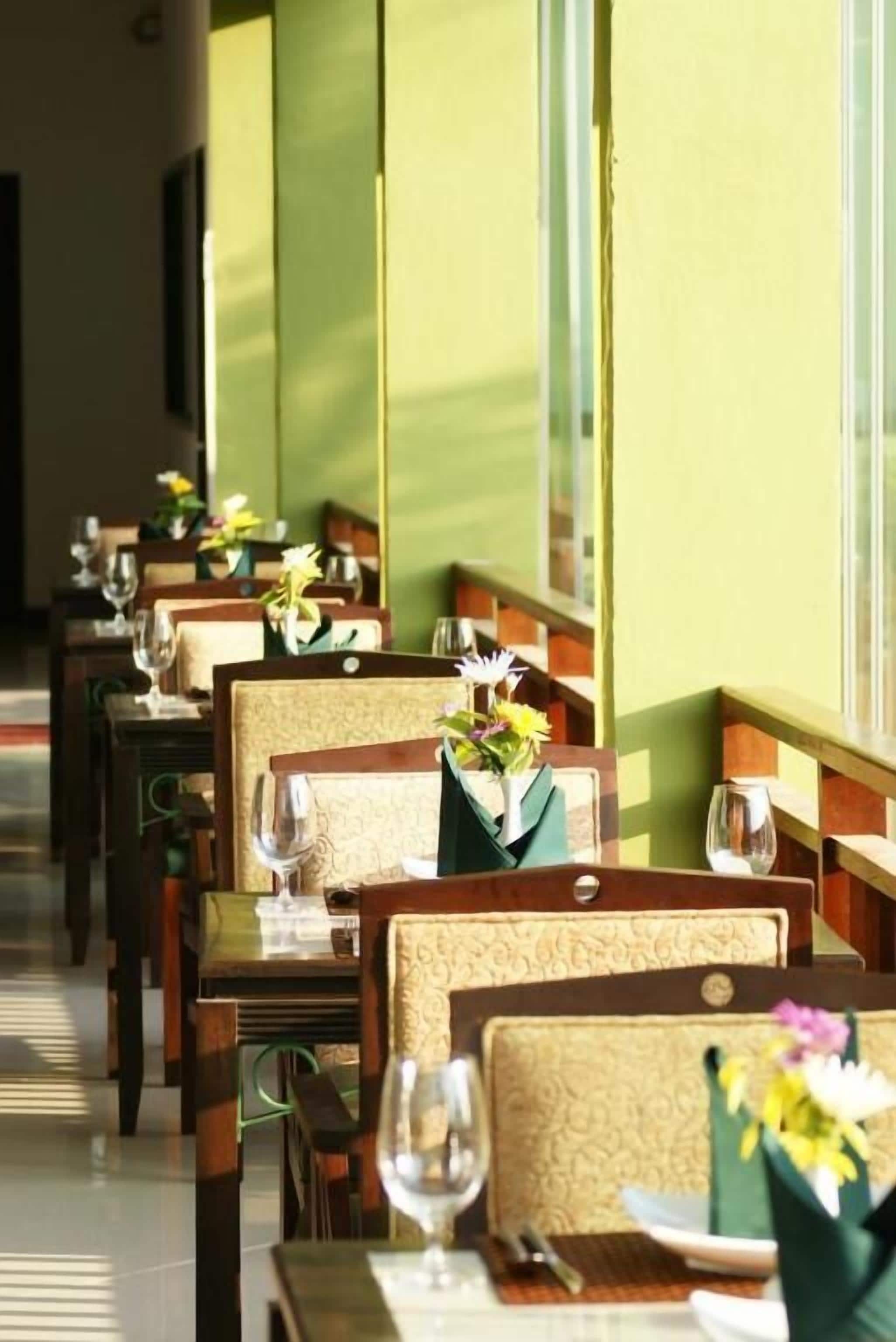 Ein Restaurant mit Reihen aus Holztischen und -stühlen, an jedem Tisch eine Blumenvase und Weingläser.