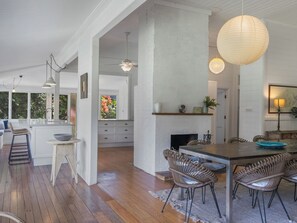 Relax in a warm and inviting space with a large open-plan living area, dining space, and kitchen, featuring a fireplace and large windows.