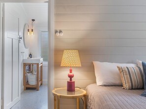 Cozy bedroom with a neatly made bed, reading table, and bathroom access.