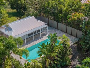 Enjoy a retreat with a large pool and patio area surrounded by lush greenery.