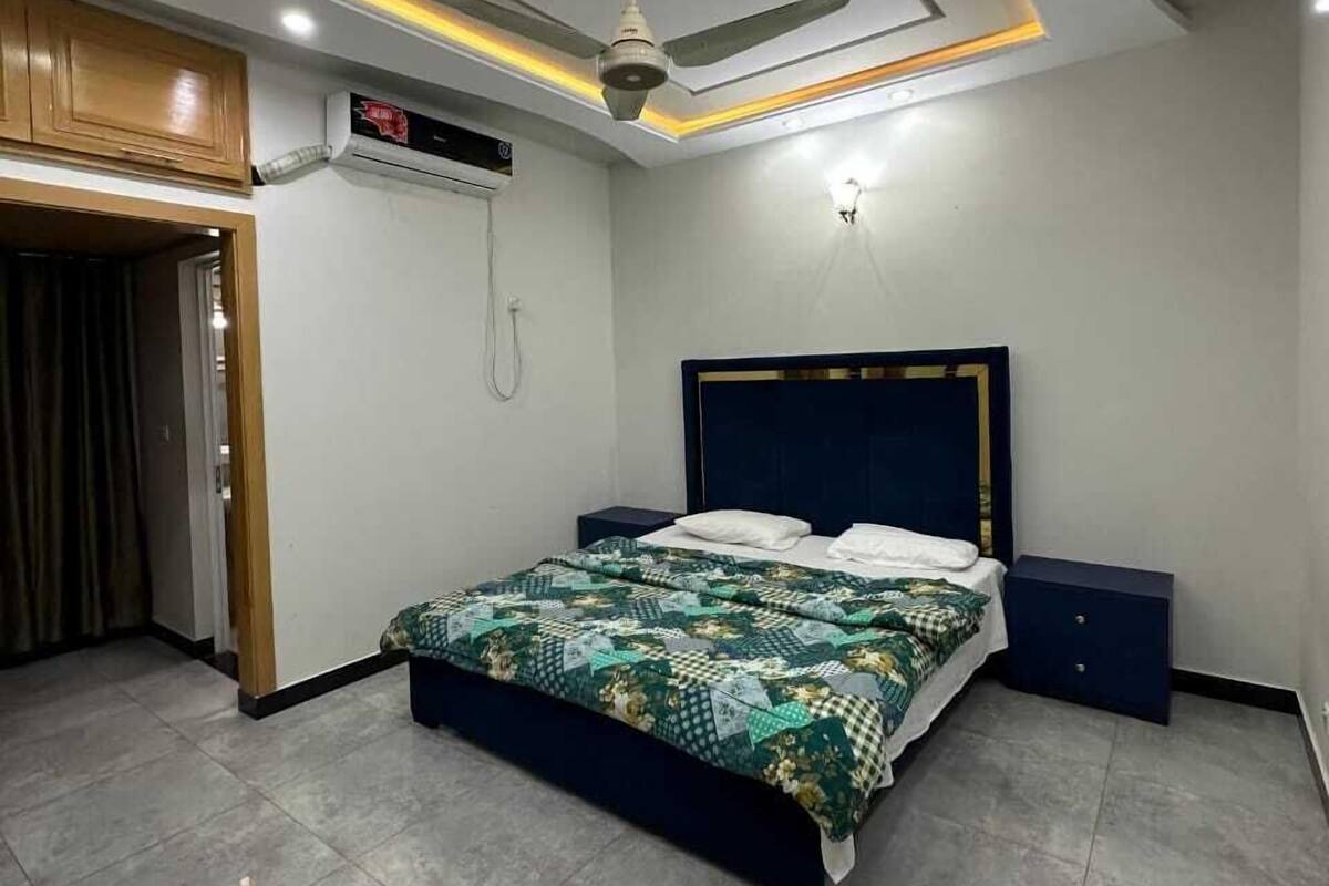 A bedroom with a bed, a ceiling fan, recessed lighting, a wardrobe, and a built-in air conditioning unit.