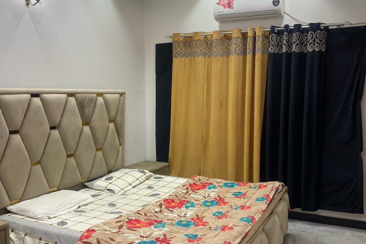 A bedroom with a bed, ceiling fan, recessed lighting, and a window with curtains.