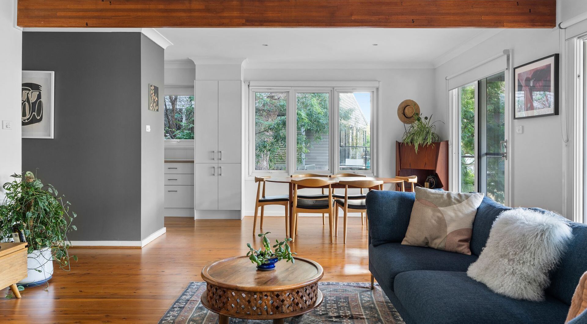 A spacious living area with a blue sofa, wooden coffee table, and a dining table with chairs.