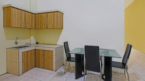 A compact kitchen with a sink, cabinets, and a dining table with chairs. - Hotel O Atlanta Guesthouse (Semarang)