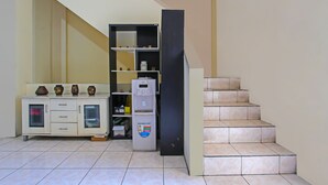 A kitchen area with a refrigerator, cabinets, and a staircase. - Hotel O Atlanta Guesthouse (Semarang)