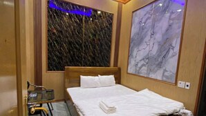 A hotel room with a large bed, a small desk with a chair, a marble floor, and a large marble wall. - Ha Chau Homestay (Mu Cang Chai)