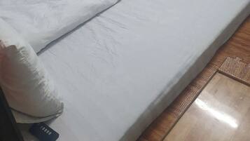 Ein Einzelbett mit weißer Bettwäsche in einem Zimmer mit blauen Wänden und einem Holz-Kopfteil.