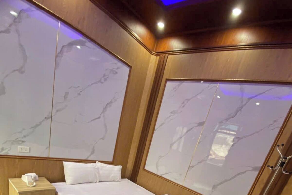 A bedroom with a bed, wooden nightstand, marble-patterned walls, and a wooden door.