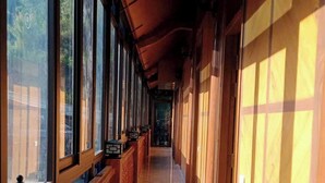 A corridor with wooden railings and large windows, leading to a door at the end. - Ha Chau Homestay (Mu Cang Chai)