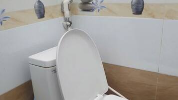 A bathroom with a toilet, a bidet, and a mop bucket.