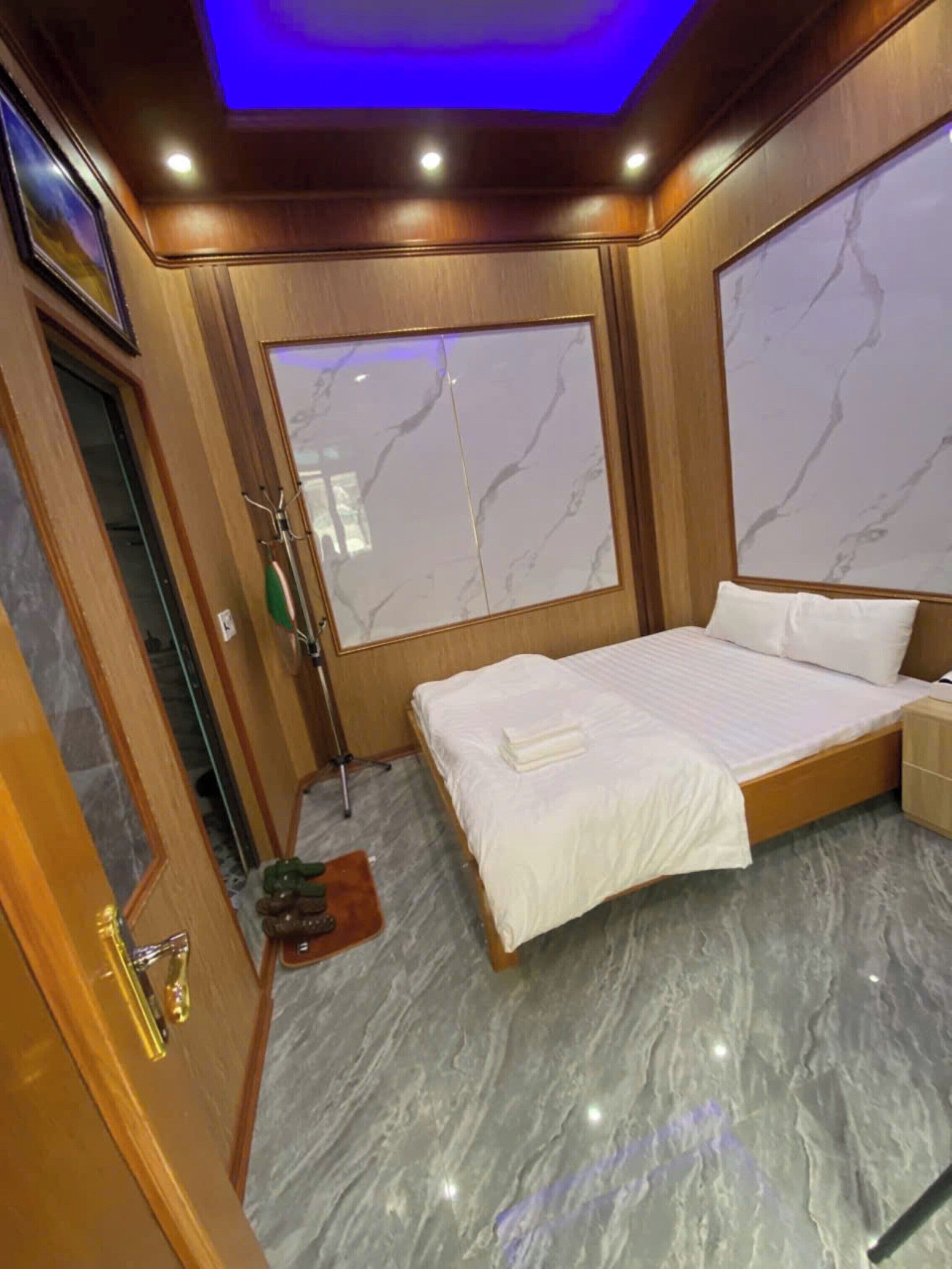 A bedroom with a bed, a shower, and a large window with a marble wall.