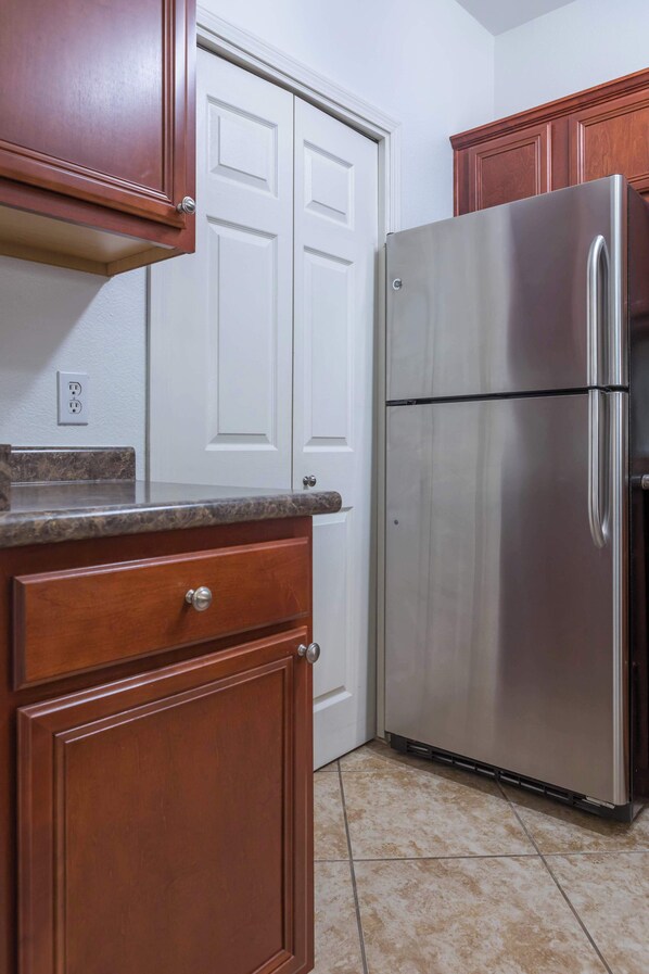 A kitchen with wooden cabinets, a stainless steel refrigerator, and a white door.