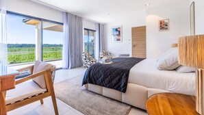 A modern bedroom with a large bed, a seating area with a view, and a balcony with curtains. - Suite "La Sunset" - Heated pool & SPA (Plaissan)
