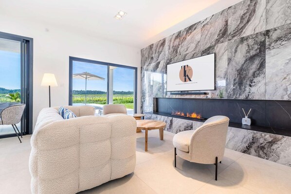 A modern living room with a fireplace, comfortable seating, and a large window offering a scenic view.