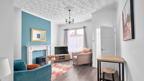 Una sala de estar con chimenea, televisor, sofá, mesa de centro y un comedor con una silla.