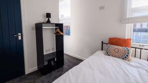 A bedroom with a bed, a wardrobe, a window with blinds, and a door. - Fabulous 6 bedroomed, all en-suite accommodation (Hartlepool)