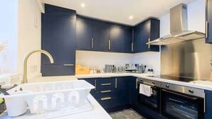 A modern kitchen with dark cabinetry, stainless steel appliances, and a white countertop. - Fabulous 6 bedroomed, all en-suite accommodation (Hartlepool)