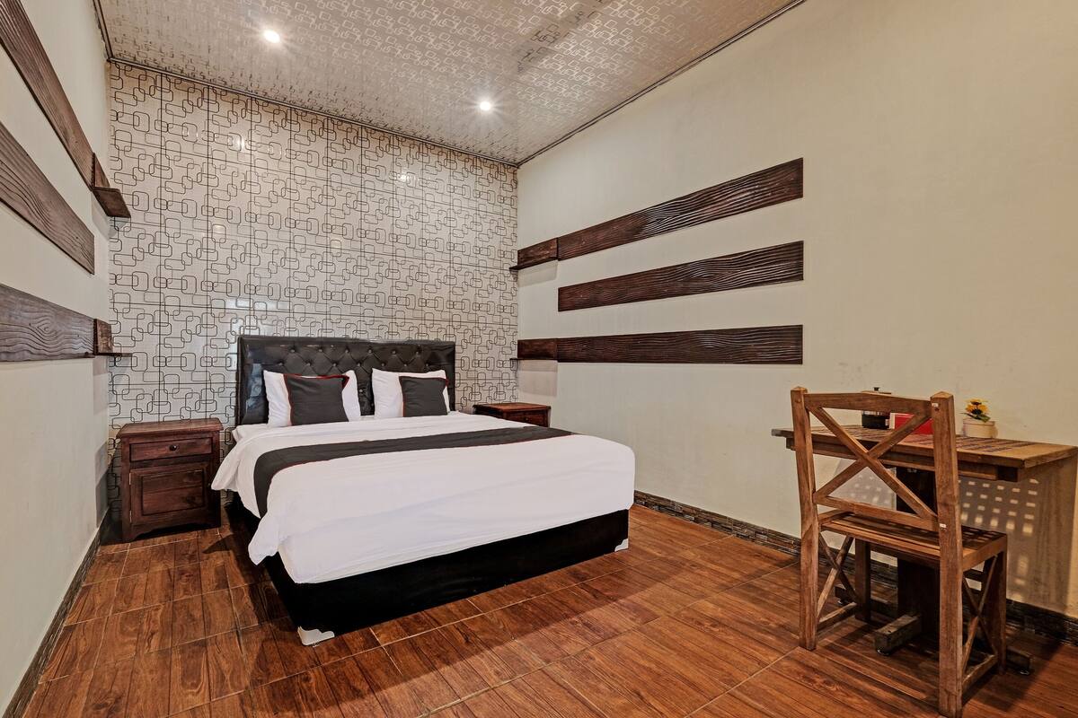Un dormitorio con una cama, mesitas de noche de madera, un escritorio y una silla.