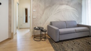 A modern living room with a grey sofa, a small round table, and a patterned rug.