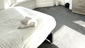 Une chambre à coucher avec un lit, une télévision, une commode et de grandes fenêtres.