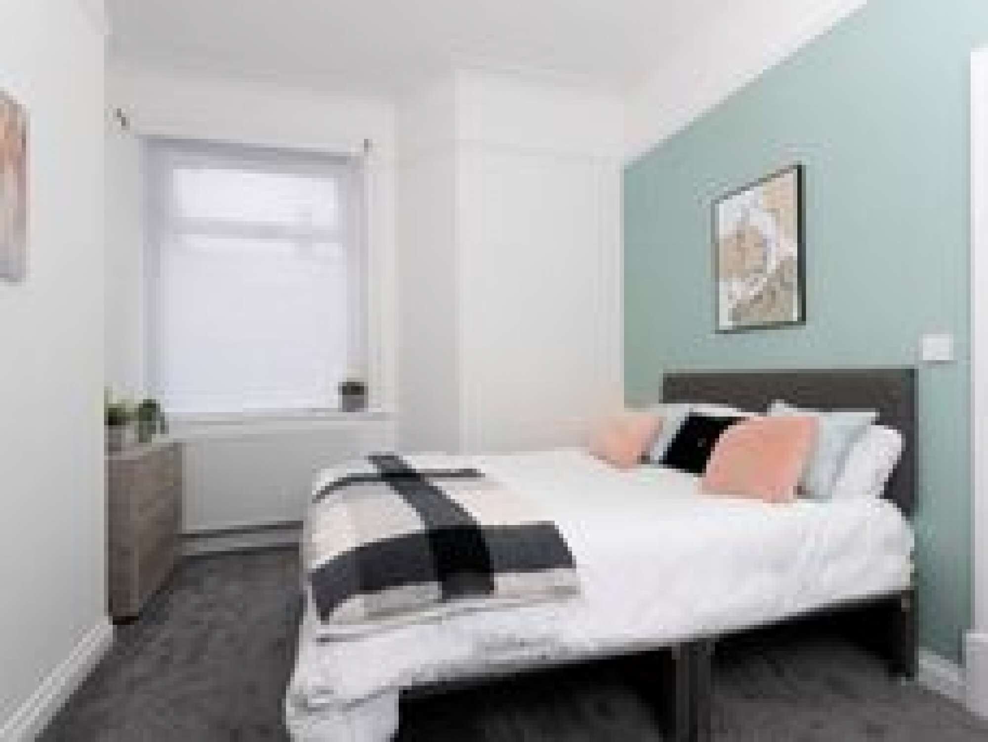 Une chambre à coucher avec un lit, une fenêtre et un tableau accroché au mur.