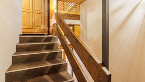 Una escalera de madera con barandilla que lleva a un cuarto con armarios de madera y un separador de celosía.