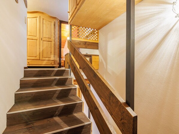 A wooden staircase with a handrail leading to a room with wooden cabinets and a lattice partition.