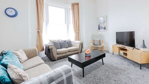 Ein Wohnzimmer mit einer Couch, einem Couchtisch, einem Fernseher und einem Bücherregal.