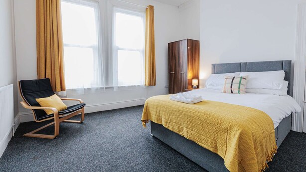 Ein Hotelzimmer mit Bett, Stuhl, Kleiderschrank und einem Vorhangfenster.