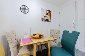 A dining area with a wooden table, two chairs, a clock, and a painting on the wall. - 5 Bedroom House in Hartlepool (Hartlepool)
