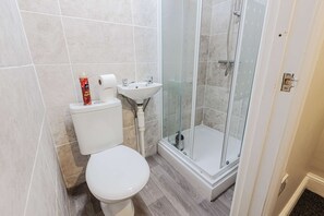 A bathroom with a toilet, sink, and glass-enclosed shower. - 5 Bedroom House in Hartlepool (Hartlepool)