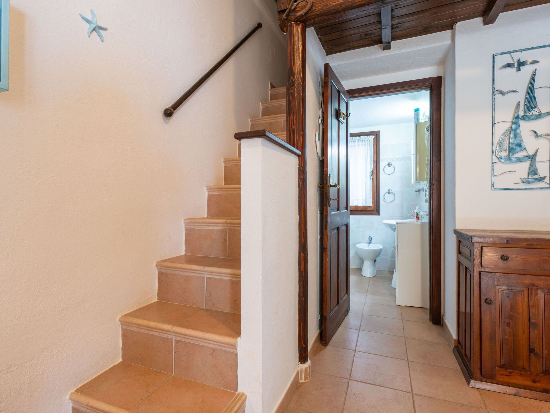 Un escalier menant à une salle de bain équipée de toilettes et d’un lavabo.