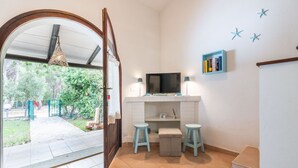 Una habitación con televisión, dos taburetes, una mesita y una estantería.