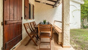 Un patio rústico al aire libre con una mesa y sillas de madera, un colgante de luz y una pared de piedra.