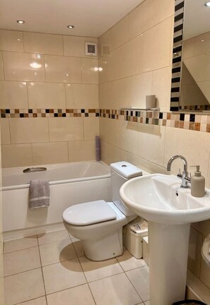 Ein modernes Badezimmer mit Badewanne, Toilette und Waschbecken.