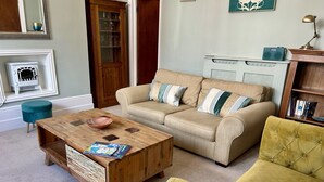 Ein Wohnzimmer mit Couch in Beige, gelbem Sessel und einem Holztisch.