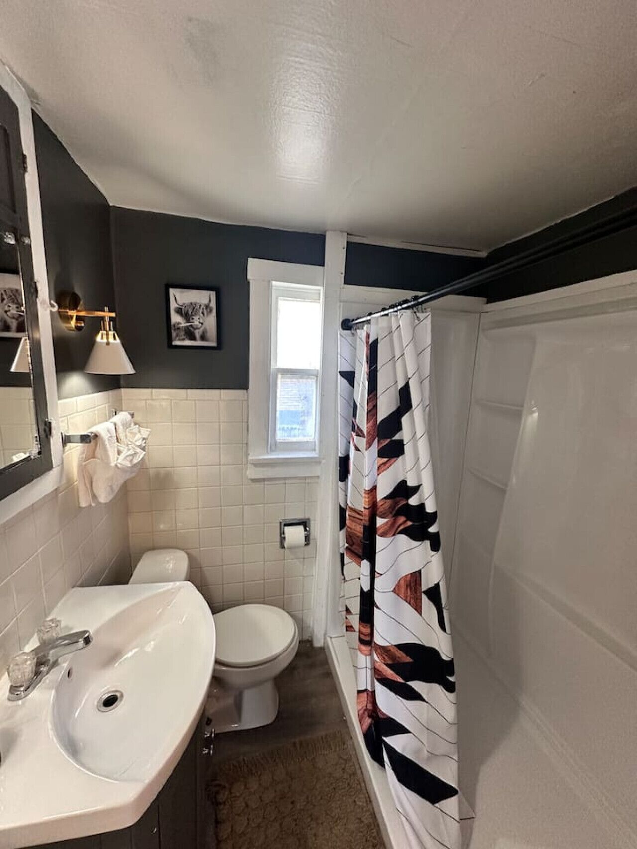 Un baño con lavamanos, inodoro y cortina de ducha de diseño geométrico.