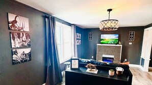 Un salon moderne avec un canapé noir, une table basse et une cheminée.