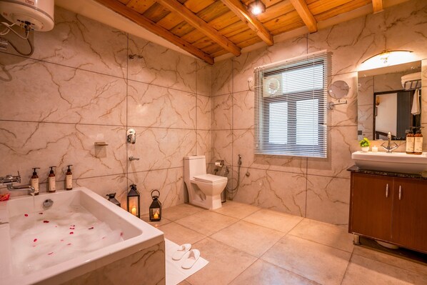 A bathroom with a marble floor, a bathtub, a toilet, and a sink with a mirror. - Moustache Select Naukuchiatal By the Lake (Nainital)
